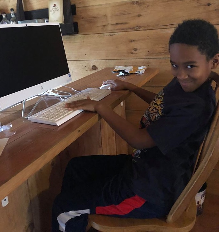 Smiling Appalachian student using new all-in-one computer at home through Americans Helping Americans digital divide program