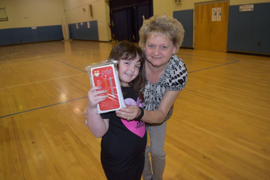 A young student in Lee County Kentucky smiles while receiving her own Mighty Molar dental kit for hygiene.