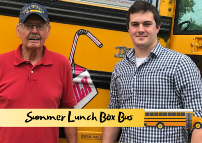 A Navy veteran and a volunteer stand together in front of the Tennessee Summer Lunch Box Bus.