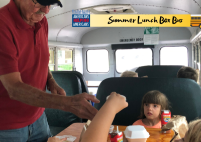 A volunteer on the Lunch Box Bus serves a nutritious meal to a young student in a low-income Tennessee community.