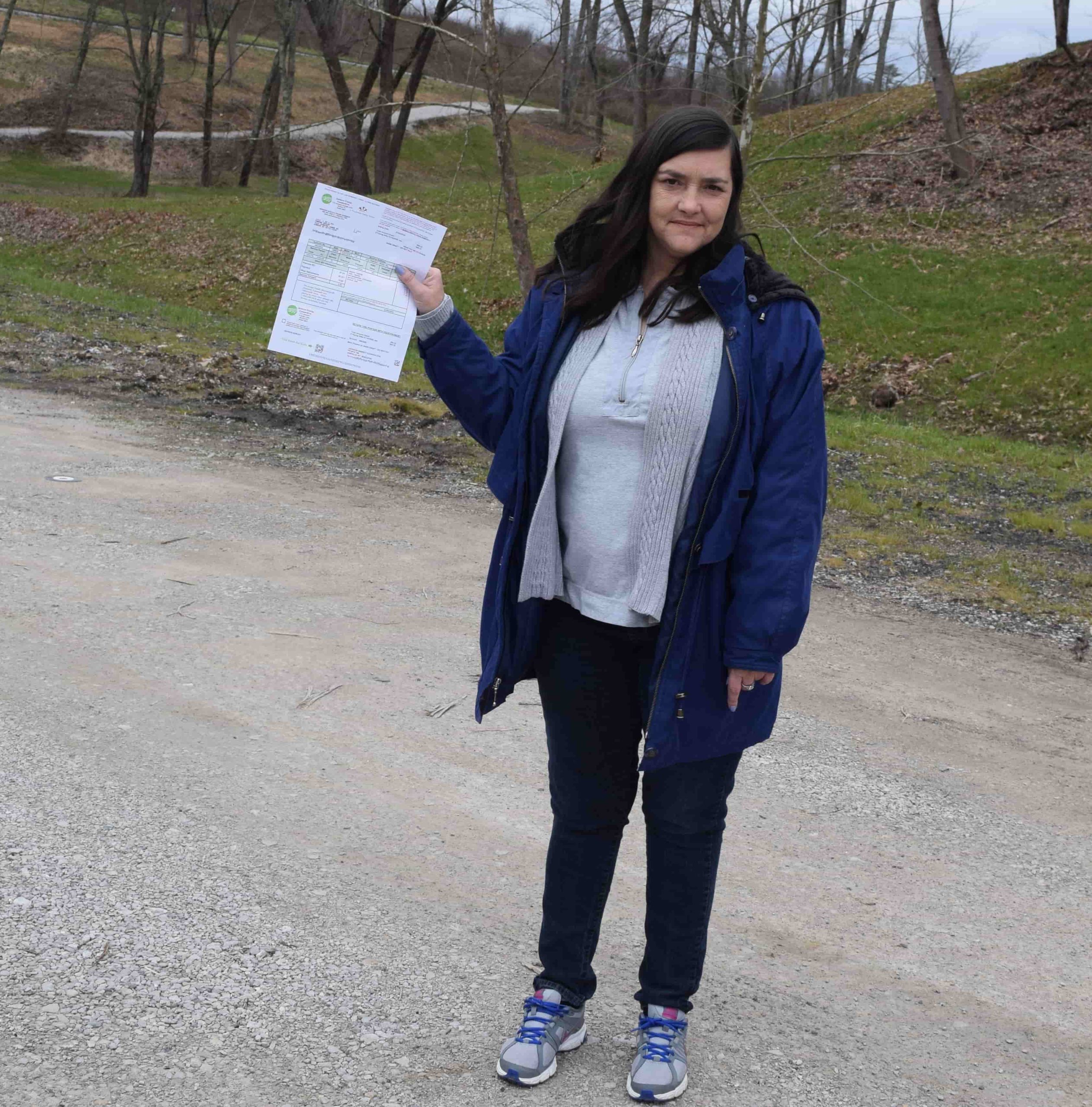 A mother in Georgia holds a utility bill, representing families supported by Caring Hands and Americans Helping Americans.