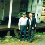 Two men standing outside a worn Appalachian home.