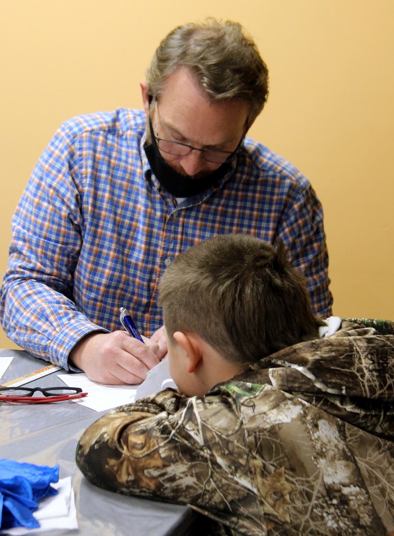 Volunteer helping Hancock County boy sign up for free eyeglasses through Americans Helping Americans program.