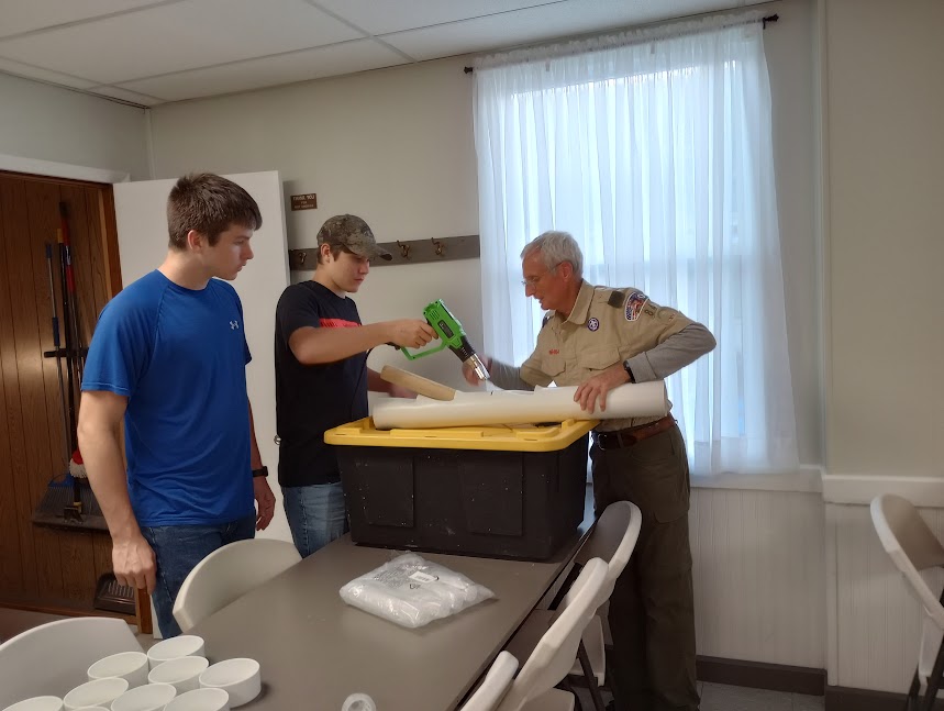Teen volunteers and scout leader assemble a PVC hydroponic tower