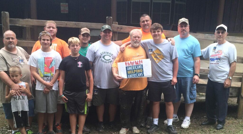 Volunteers in Appalachia gather with an Americans Helping Americans sign after completing a home rehab project.