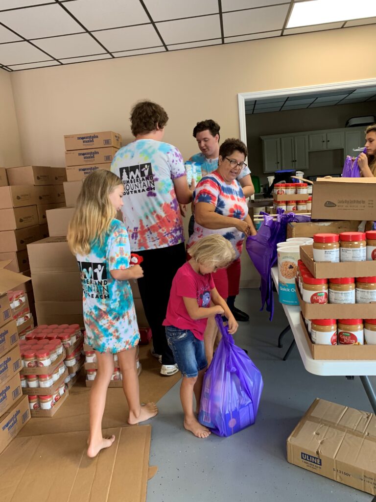 Cumberland Mountain Outreach volunteers (adults and kids) pack pantry bags with peanut butter and groceries in Appalachia.