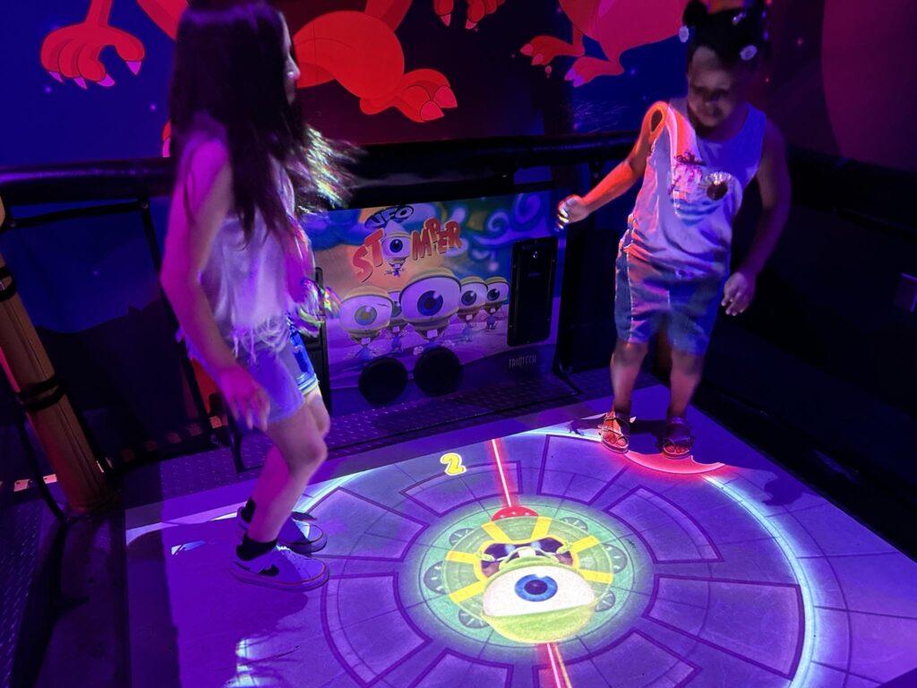Children enjoying the UFO Stomper interactive science game at WonderWorks during their Smoky Mountains summer camp trip.