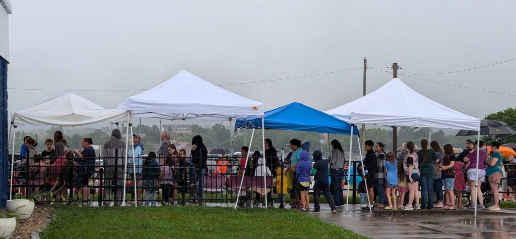 A festive mood remains as families wait under canopies for school supplies and dental kits in Jefferson City, TN.