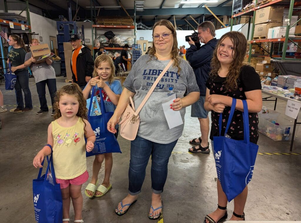 A mother and her daughters receive bags of school supplies at the AMOS Back to School event in Tennessee.