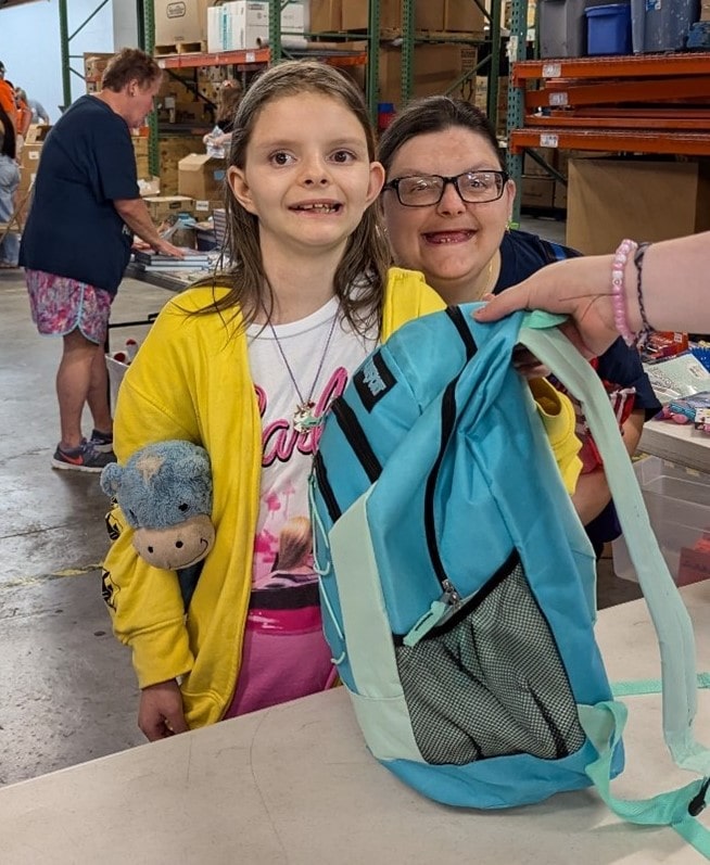 A third-grade student smiles after receiving her first new backpack at the AMOS community event in Tennessee.