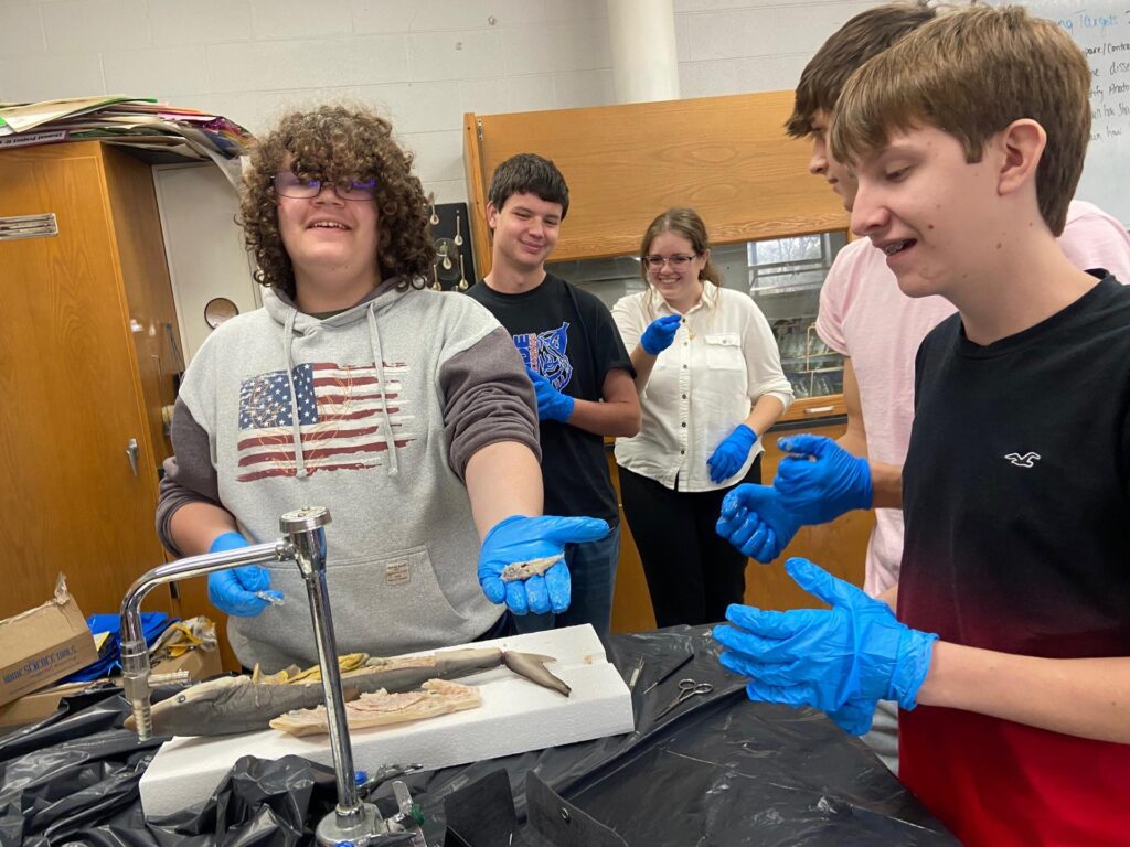 High school students in an Appalachian Title 1 school smiling as they dissect specimens in biology class with blue gloves on