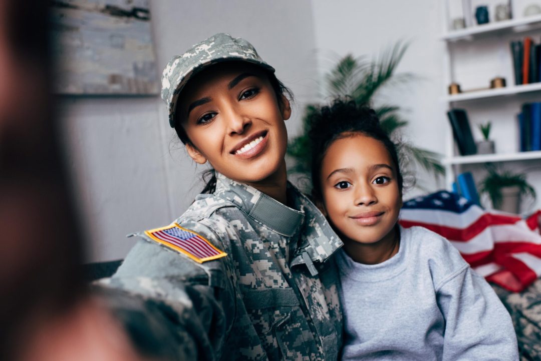 A female veteran and child smile together, representing the Americans Helping Americans housing support in Virginia.