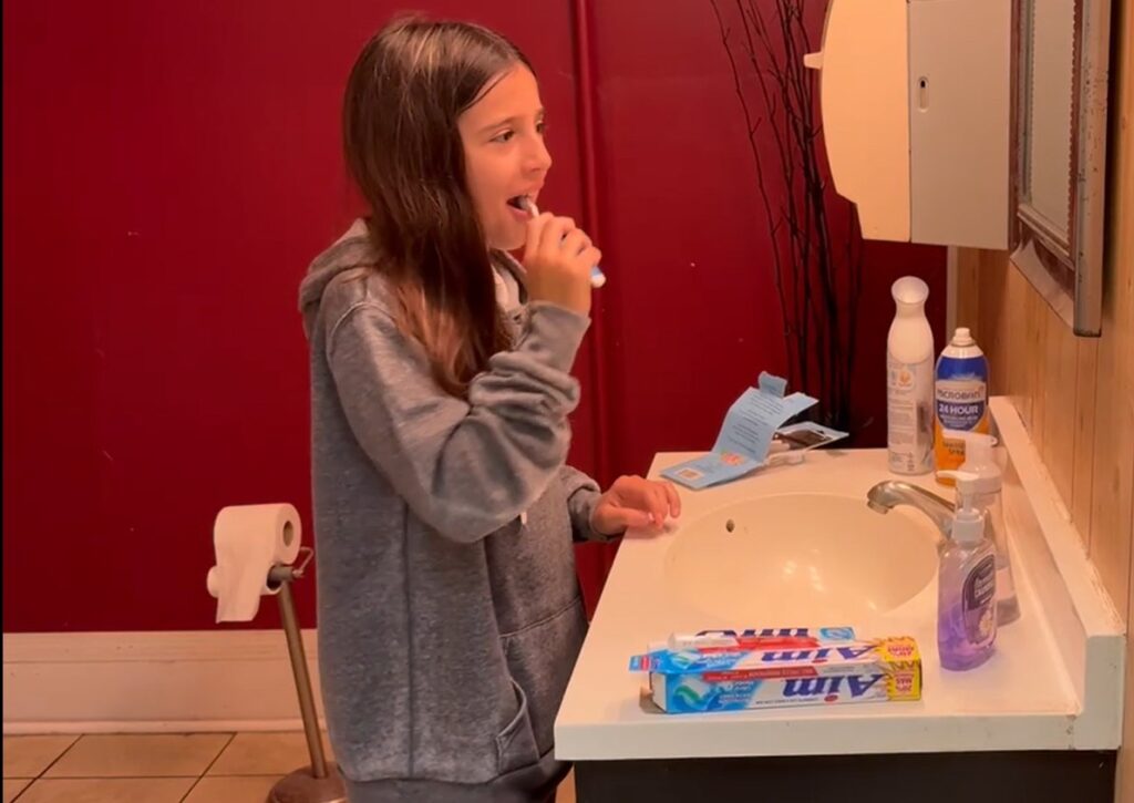 Girl in Appalachia brushing her teeth with Mighty Molars dental kit from Americans Helping Americans.
