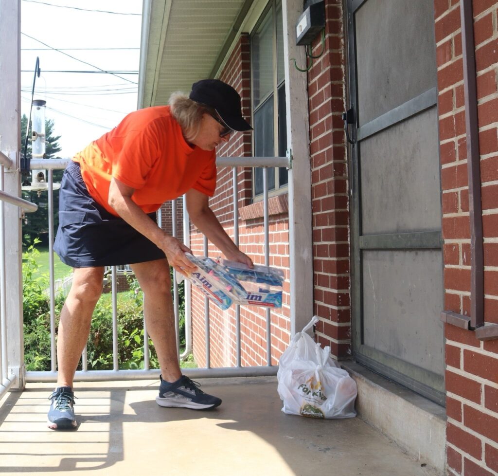 Pam delivers food and hygiene kits to a child’s doorstep for the Americans Helping Americans Lunch Box program.