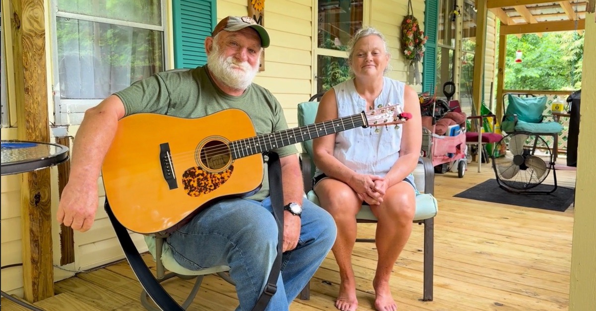 Homeowners standing on newly repaired porch after home rehabilitation support