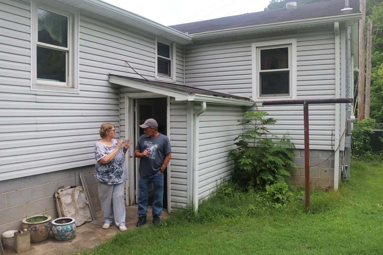 AHA — BCPIA FY25 Home Rehab Rita Dameron Scottie Perez SH photo June 2025 Rita Dameron speaking with BCPIA volunteer Scottie Perez outside her flood damaged home in McDowell County West Virginia