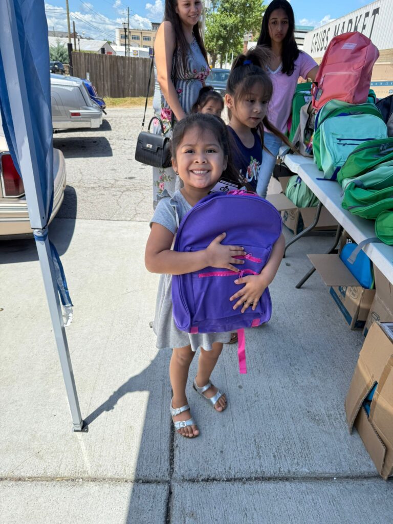 Smiling child with a new school backpack at a Lamp Ministries outreach event in Gainesville, Georgia.