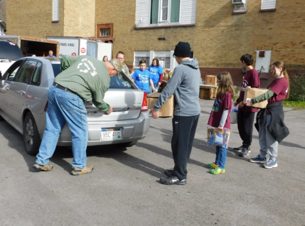 Volunteers loading food boxes donated by Americans Helping Americans® into a car to support families in need.